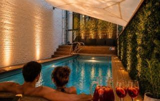 Couple dans la piscine extérieure privée avec une cruche de sangria au coucher du soleil